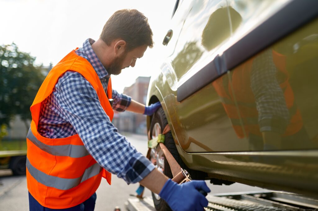 Tow truck operator fixing car on platform